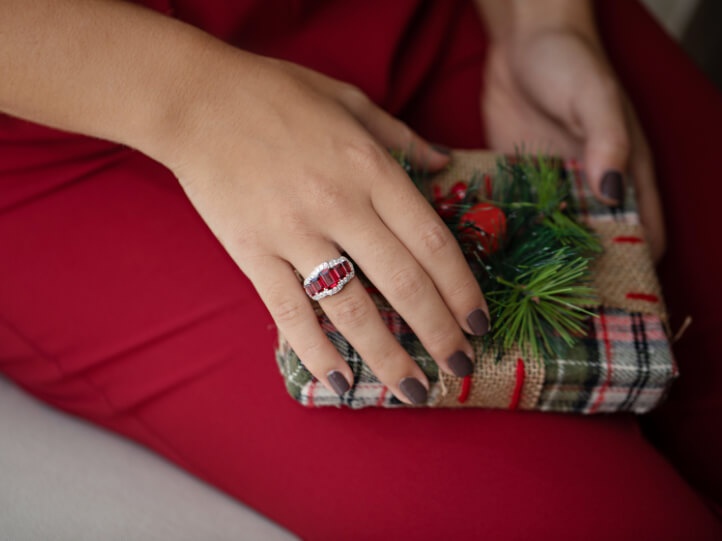 Woman wearing a ring holding a holiday gift box