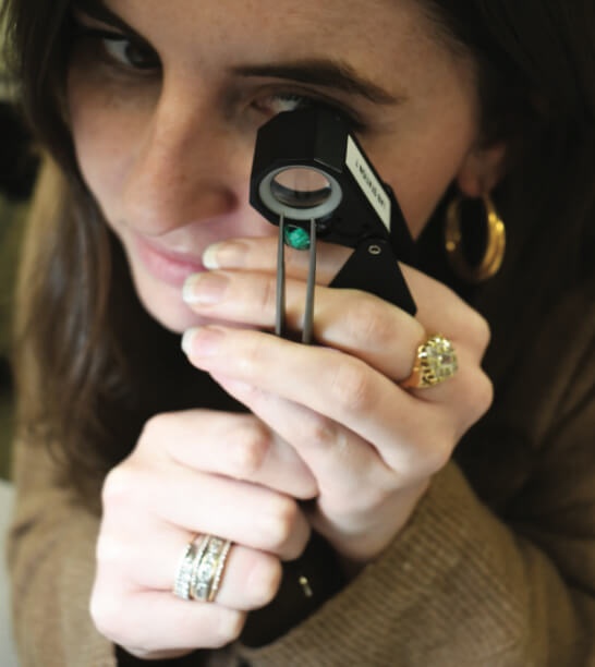 Woman viewing a gemstone through a loupe 