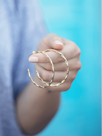 Woman holding gold hoop earrings