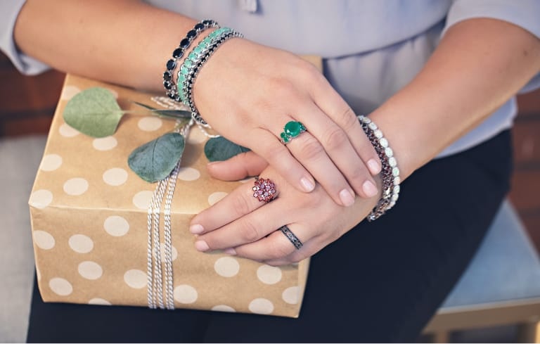 image of hands wearing rings and bracelets holding a box 