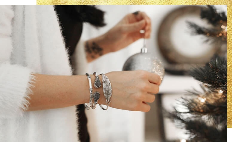 Woman wearing bracelets holding a holiday ornament 